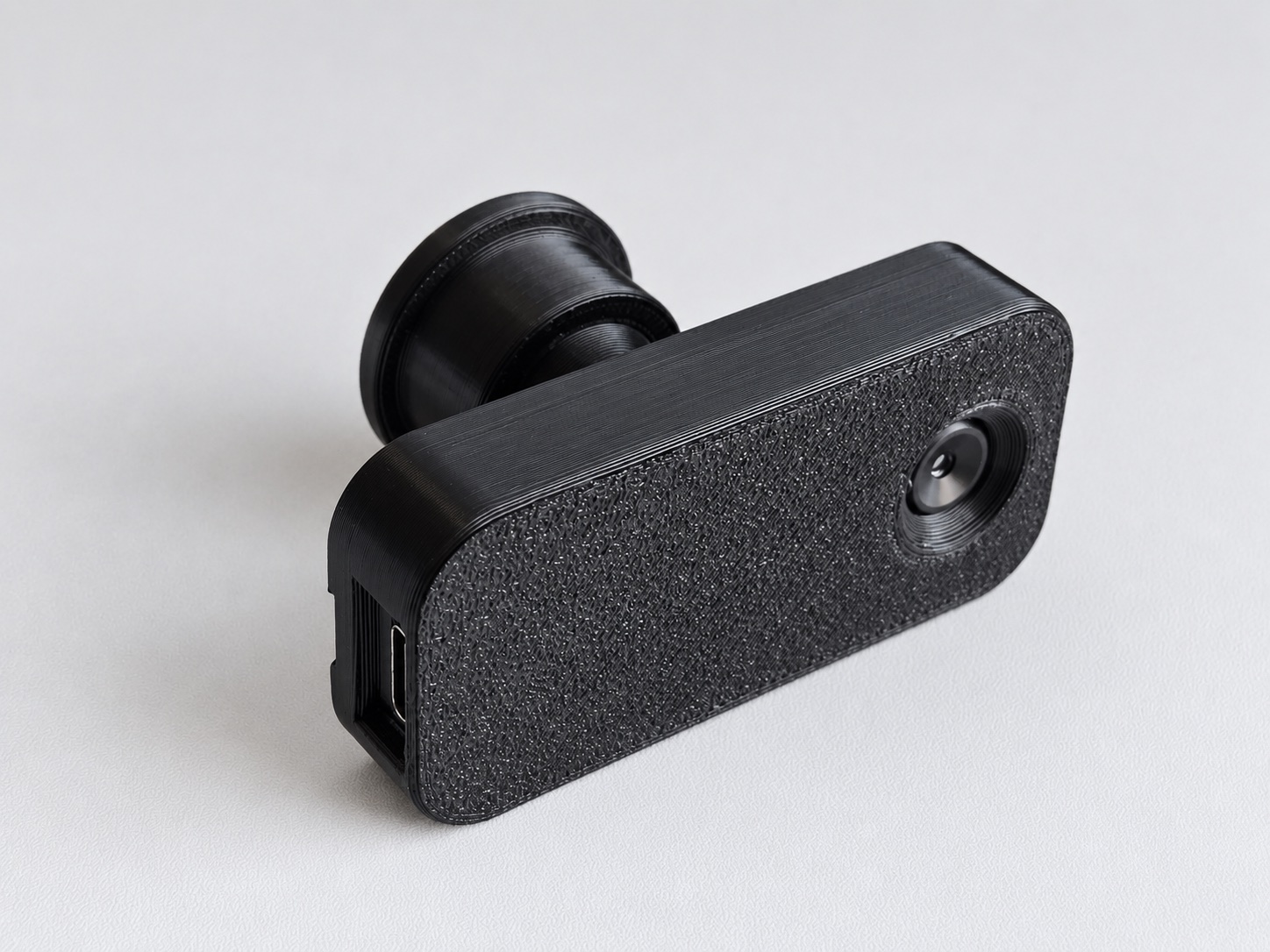 An angled close-up of the black StoveDetector, showing its printed texture, heat-sensor window, USB-C port and ball-joint mount.