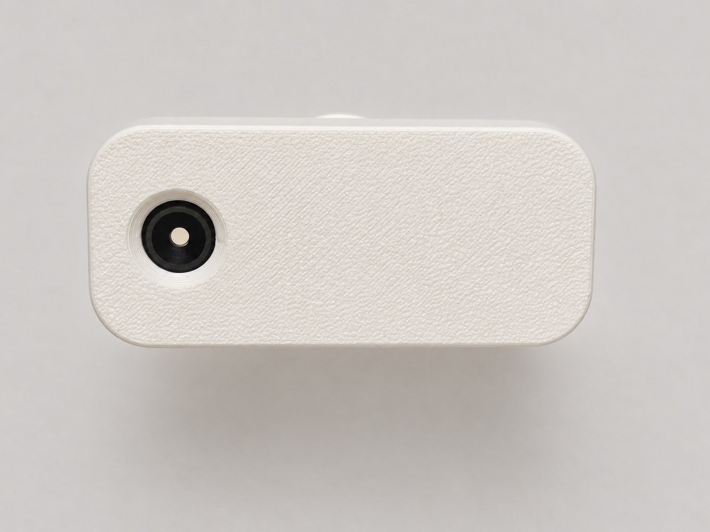 A straight-on close-up of the white StoveDetector, showing its printed texture and round heat-sensor window.